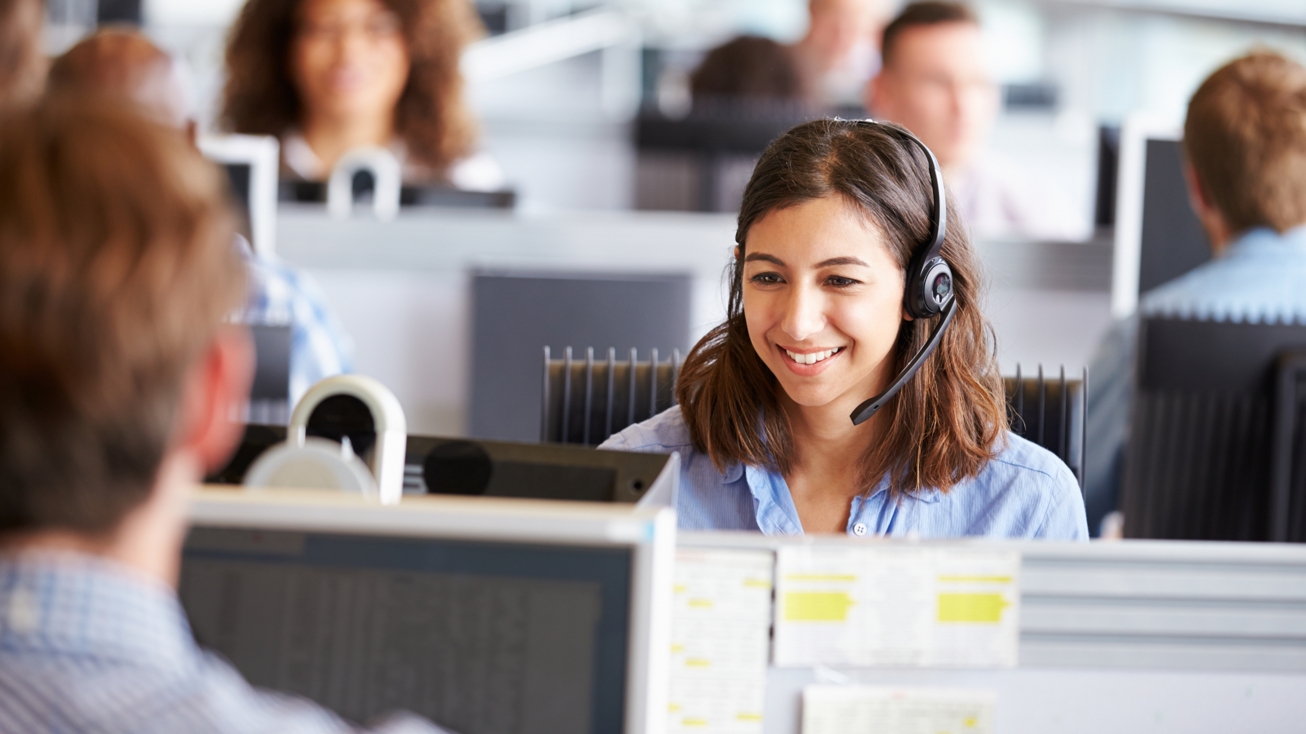 Call centre worker, wearing headset to access VoIP business phone system.